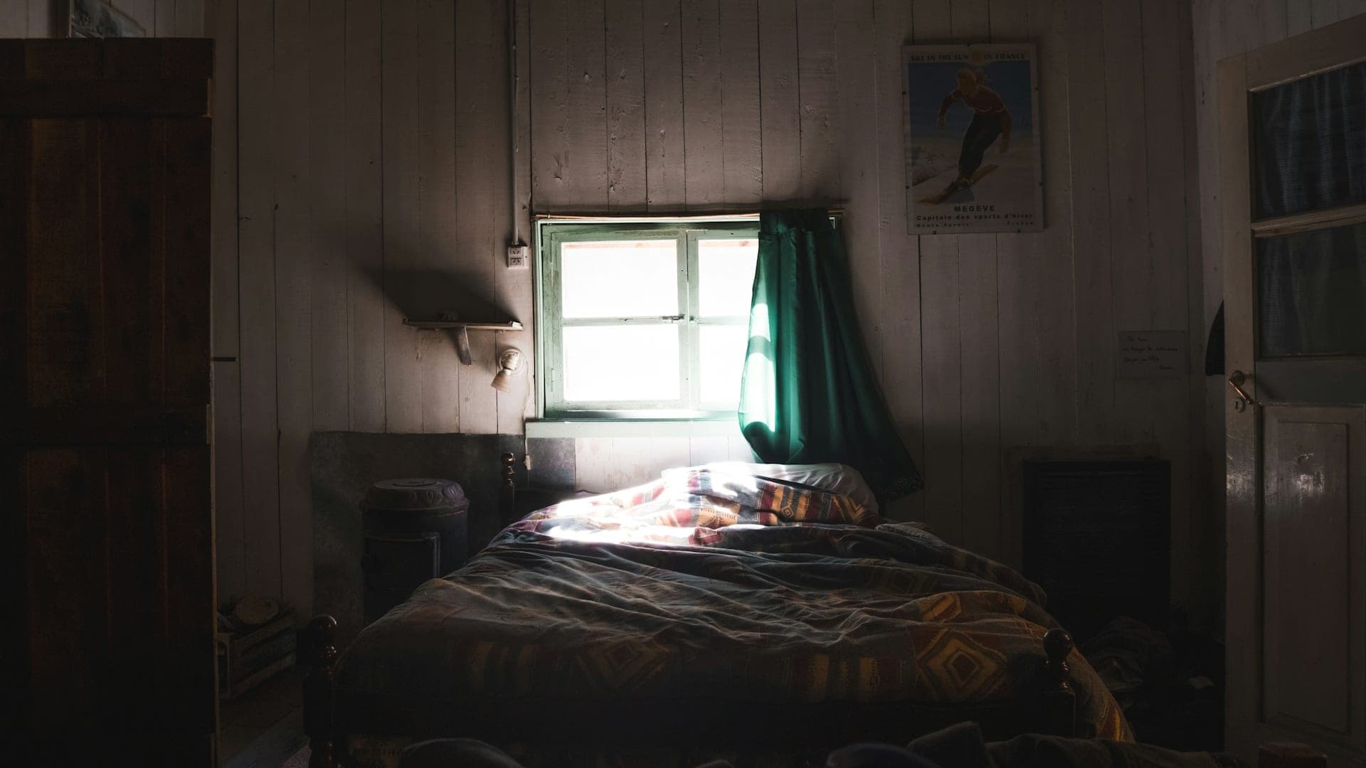 Furnished spare bedroom in a mountain home with a made bed and a window onto snowy woods