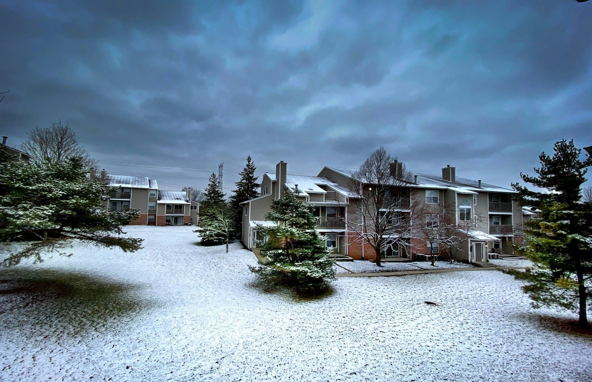 Snow-covered condo buildings at the base of a ski area on a winter afternoon